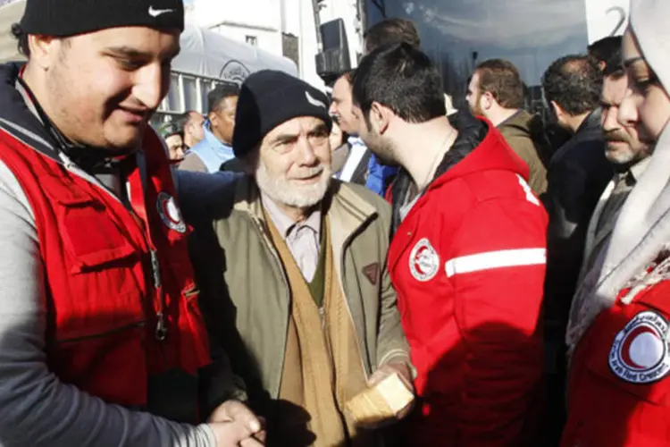 
	Membros do Crescente Vermelho da S&iacute;ria ajudam um homem durante a retirada da &aacute;rea sitiada de Homs, na S&iacute;ria
 (Khaled al-Hariri/Reuters)