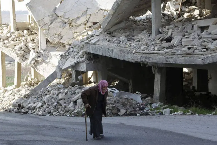 
	Mulher anda em frente a constru&ccedil;&atilde;o bombardeada na S&iacute;ria
 (REUTERS/Khalil Ashawi)