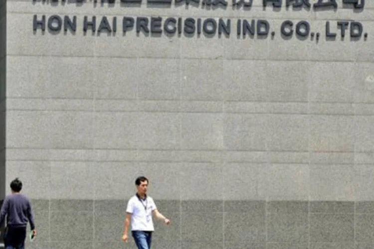 
	Trabalhadores passam por uma f&aacute;brica da gigante Hon Hai em Tuchung, Taiwan
 (Patrick Lin/AFP)