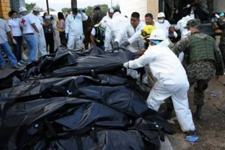 Soldados e legistas retiram corpos da penitenciária de Comayagua (Orlando Sierra/AFP)