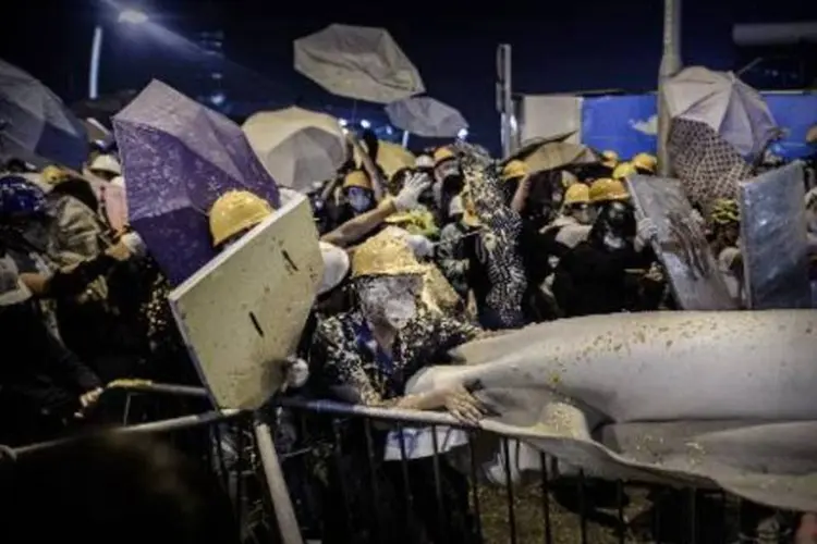 Protestantes pró-democracia recebem jatos de spray de pimenta durante barricada feita em confronto com as forças policiais em Hong Kong  (Philippe Lopez/AFP)