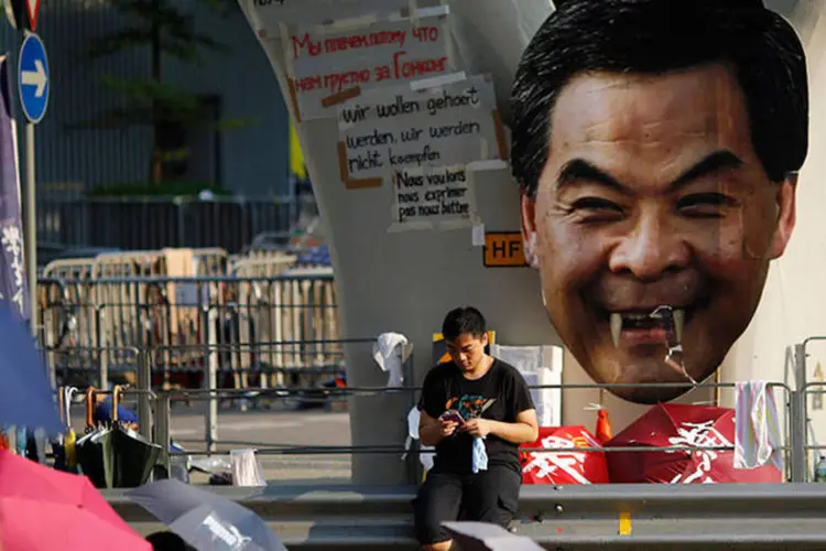 
	Manifestante senta pr&oacute;ximo &agrave; imagem do chefe executivo de Hong Kong, Cy Leung
 (REUTERS/Carlos Barria)