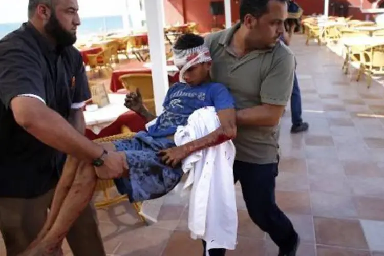 Funcionários de um hotel de Gaza socorrem um menino ferido (Thomas Coex/AFP)