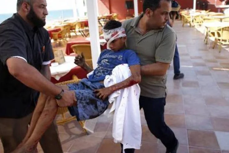 Funcionários de um hotel de Gaza socorrem um menino ferido (Thomas Coex/AFP)