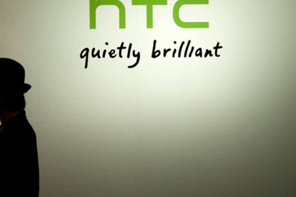 Homem parada em frente a logo da HTC (Tomohiro Ohsumi/Bloomberg)