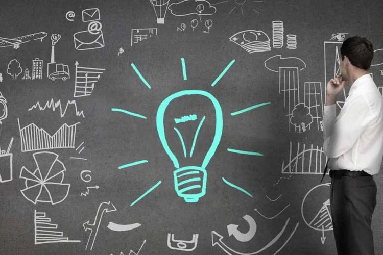 Empreendedor tendo uma ideia (desenha uma lâmpada em lousa) (Wavebreakmedia Ltd/Thinkstock)