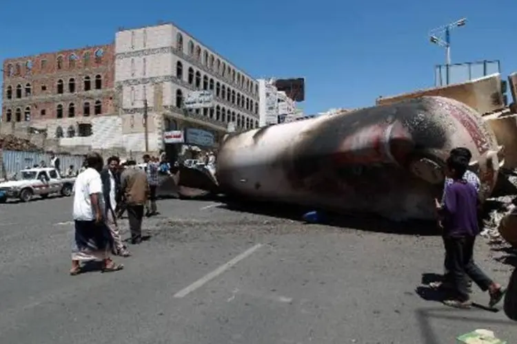 Iemenitas observam caminhões-tanques queimados durante confrontos na capital Sana (Mohammed Huwais/AFP)
