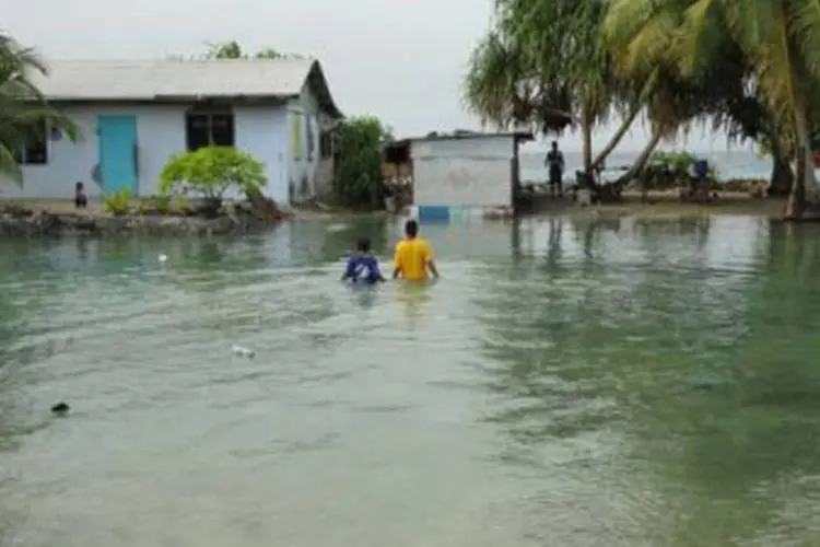 Dois moradores de Majuro caminham em meio à inundação causada pela maré alta (AFP/Giff Johnson)