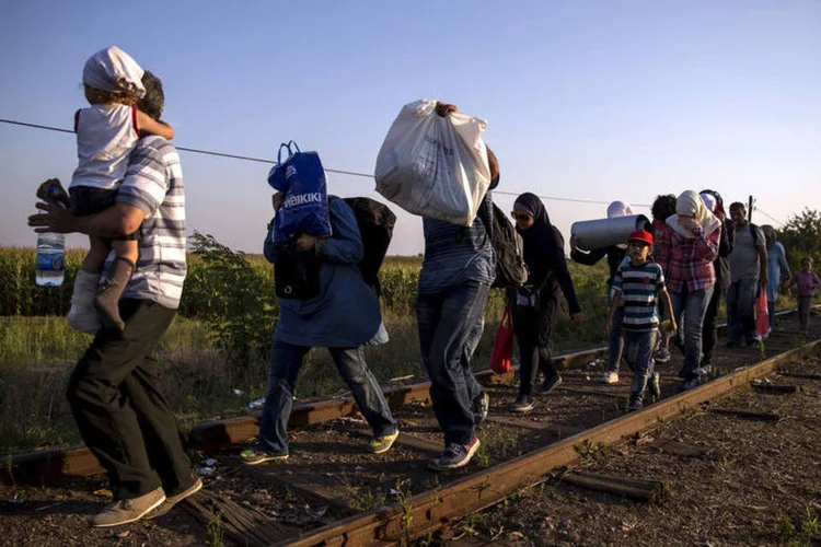 
	Imigrantes s&iacute;rios caminham em ferrovia: pelas regras da Uni&atilde;o Europeia, as pessoas que buscam asilo devem se registrar no primeiro pa&iacute;s em que entram na UE, e n&atilde;o viajar de uma na&ccedil;&atilde;o para outra dentro do bloco
 (REUTERS/Marko Djurica)