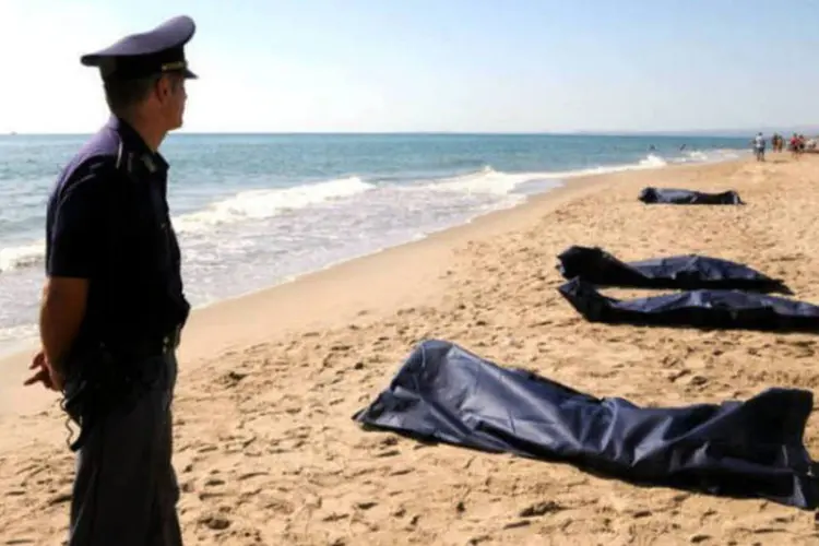 Policial junto a corpos de imigrantes que tentaram chegar à Itália, em praia de Catânia (AFP / Dario Azzaro)