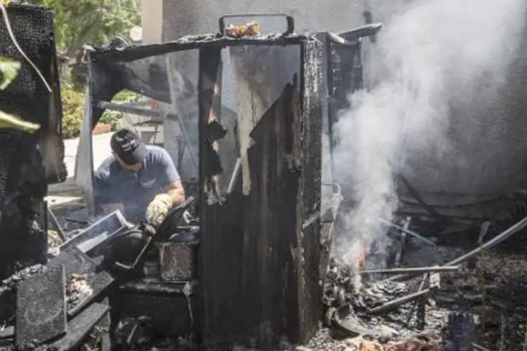 Especialista apaga incêndio provocado por queda de foguete em Kfar Aza (Jack Guez/AFP)