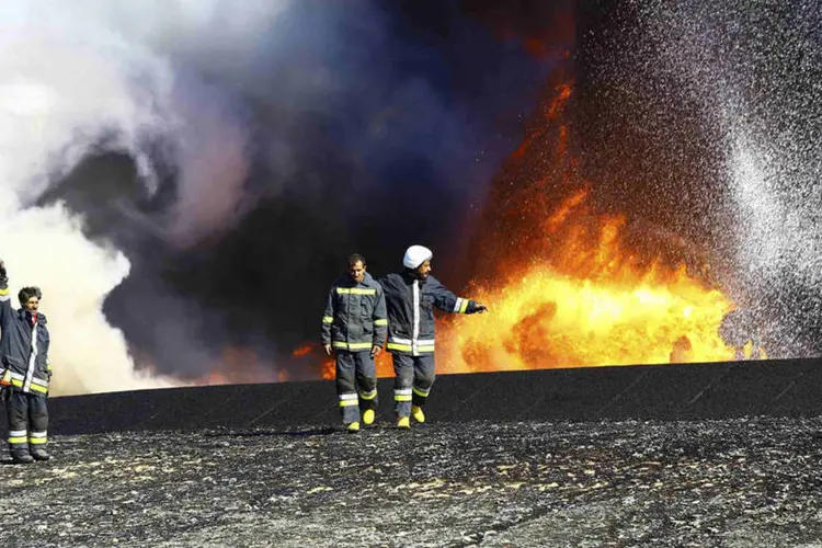 
	Inc&ecirc;ndio em tanque de &oacute;leo na L&iacute;bia: 2 terminais nas proximidades, pararam de operar tr&ecirc;s semanas atr&aacute;s, quando for&ccedil;as leais a um governo rival em Tr&iacute;poli tentaram tom&aacute;-los de for&ccedil;as aliadas
 (Stringer/Reuters)