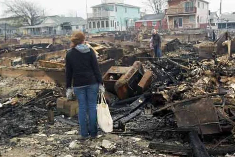 
	Mulher observa cinzas do inc&ecirc;ndio no distrito de Queens, em NY, causado por Sandy
 (Getty Images)