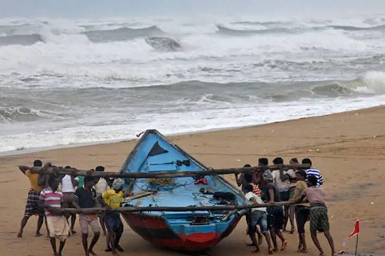 Pescadores levam barco a lugar mais seguro devido à aproximação do ciclone Hudhud (REUTERS/Stringer)