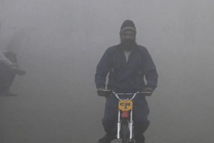 Homem anda de mini-moto em meio a uma densa neblina em uma manhã fria de inverno na cidade de Chandigarh, norte da Índia (Ajay Verma/Reuters)