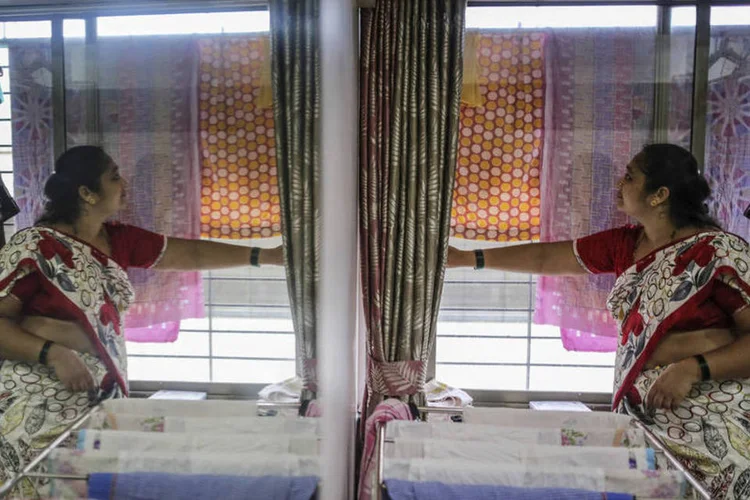 Ex-moradora de favela ajusta cortinas em seu novo apartamento em Mumbai, na Índia (Dhiraj Singh/Bloomberg)