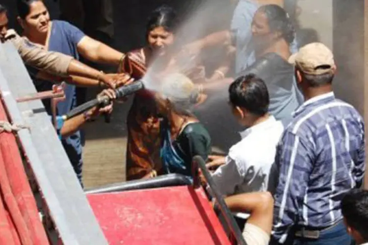 Policiais jogam água em duas manifestantes que haviam coberto o corpo de querosene, em Rajkot: os quatro sobreviventes ficaram gravemente queimados, mas o estado de saúde do grupo é considerado estável, informou (AFP)