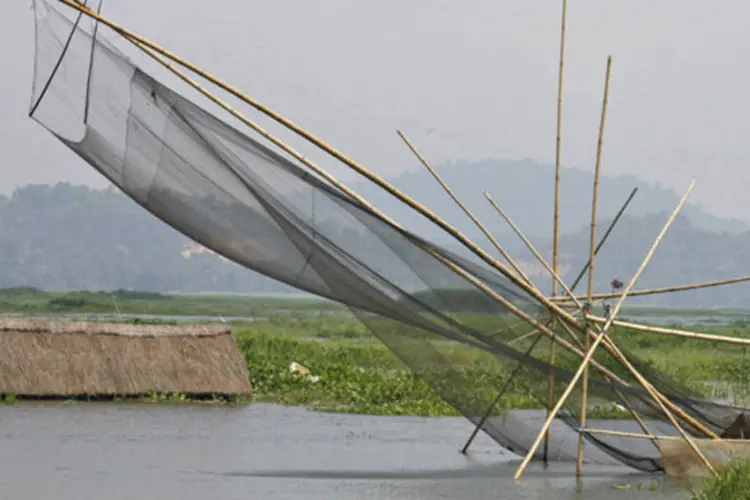 Indiano pesca em vila inundada: de acordo com as autoridades, um total de 2.174 aldeias e mais de 226 mil hectares de terra foram afetados pelas águas (REUTERS)