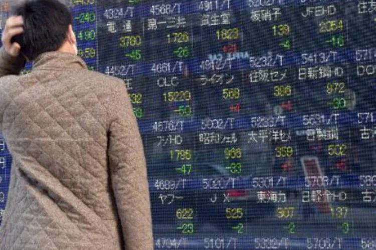 
	Homem diante de tela com os &iacute;ndices acion&aacute;rios em T&oacute;quio: internauta pergunta se h&aacute; &eacute; indicado investir um valor m&iacute;nimo em pap&eacute;is de empresas e o que pesar na escolha da corretora
 (Yoshikazu Tsuno/AFP)