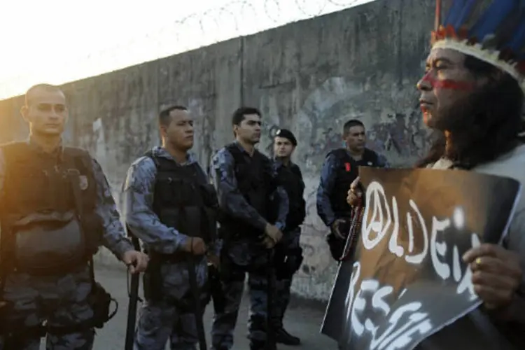 Indígena segura cartaz em frente a policiais militares durante protesto em frente ao prédio do antigo Museu do Índio, nas intermediações do Maracanã, no Rio de Janeiro (Tânia Rêgo/Abr)
