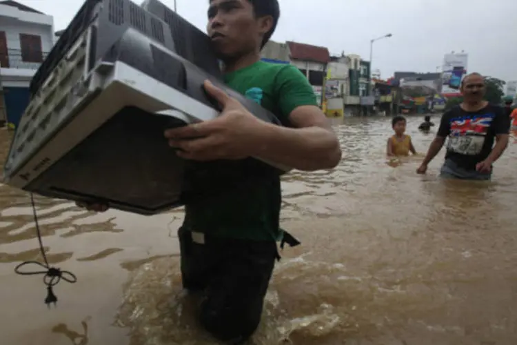 Indonésio carrega televisão durante inundação: regiões mais atingidas de Jacarta são as situadas no leste e no oeste (Supri/Reuters)