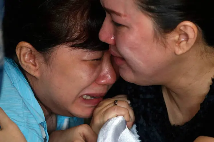 Parentes de passageiros do voo desaparecido da AirAsia choram enquanto esperam por notícias em aeroporto  (REUTERS/Beawiharta)