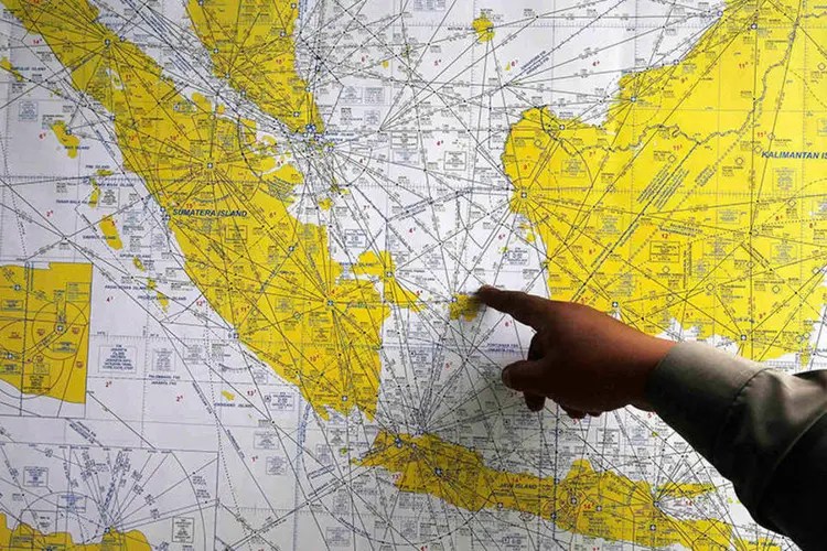 Policial da Indonésia aponta no mapa áreas de busca por avião desaparecido (REUTERS/Beawiharta)