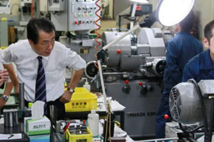 O primeiro-ministro do Japão, Naoto Kan, observa um operário numa fábrica em Tóquio (Str/AFP)