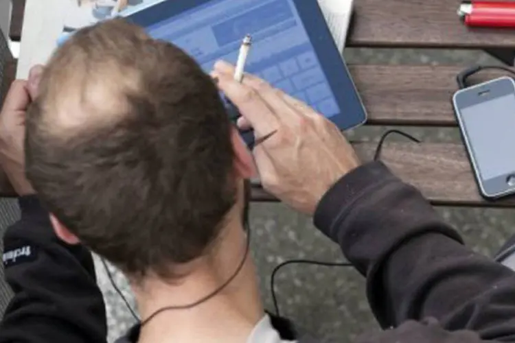 
	Homem acessa internet pelo tablet: conex&otilde;es por meio de pontos de acesso Wi-Fi s&atilde;o as preferidas
 (David Gannon/AFP)