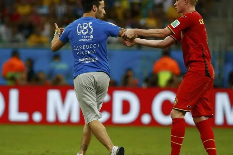 Jogador da Bélgica tenta conter torcedor que invadiu o gramado da Arena Fonte Nova, em Salvador (Michael Dalder/Reuters)