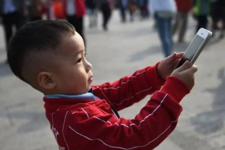 Menino usa um iPhone para fotografar em Pequim, China (Greg Baker/AFP)