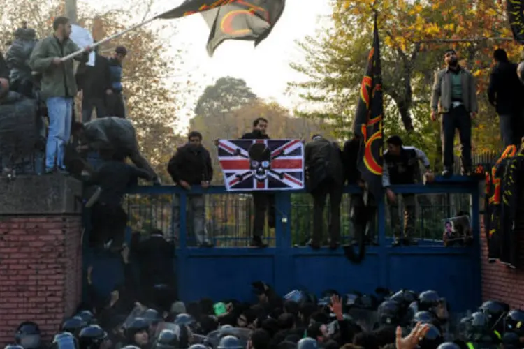 Em cima do portão da embaixada, manifestantes exibem bandeiras: eles ameaçam continuar com os protestos até que o Irã corte totalmente suas relações com o país (Getty Images)