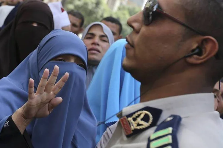 Parentes dos apoiadores do presidente deposto Mohamed Mursi fazem o gesto da Irmandade Muçulmana para um soldado egípcio, após ouvirem as sentenças de pena de morte, no sul de Cairo (Mohamed Abd El Ghany/Reuters)