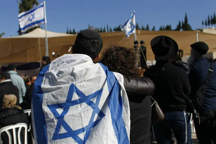 Homem com a bandeira de Israel enrolada ao corpo acompanha funeral de judeus mortos em Paris (Ronen Zvulun/Reuters)