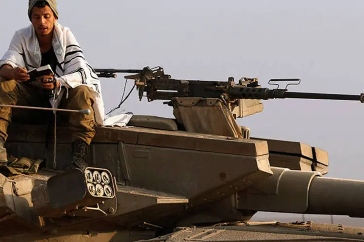 
	Soldado israelense reza em cima de um tanque militar na Faixa de Gaza: 5 soldados foram mortos hoje (28) em ataques
 (REUTERS/Baz Ratner)