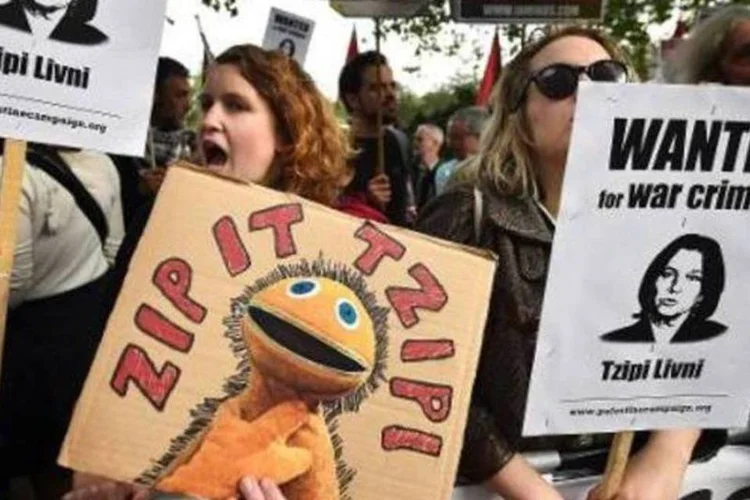 
	Manifestantes pr&oacute;-Palestina seguram cartazes com foto da ministra Tzipi Livni em Londres: &quot;Nosso interesse &eacute; resolver o conflito, e ignorar a realidade n&atilde;o &eacute; uma op&ccedil;&atilde;o&quot;, frisou a ministra (AFP/Arquivos)