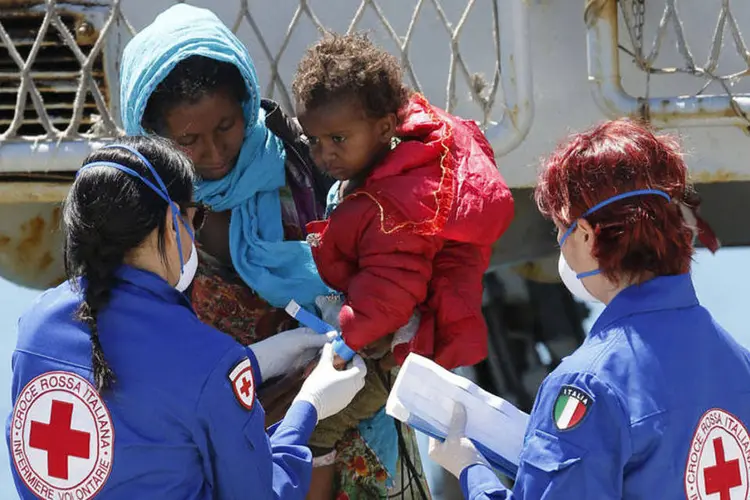 
	Mulher recebe ajuda para desembarcar de navio da Marinha da It&aacute;lia em porto na Sic&iacute;lia: 40 que viajavam com eles morreram
 (REUTERS/Antonio Parrinello)