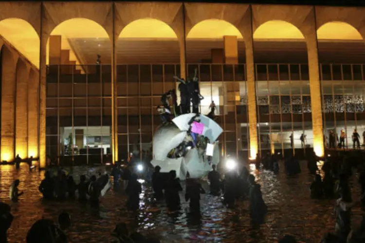 
	Manifestantes sobem em monumento durante protesto em frente ao Pal&aacute;cio Itamaraty, em Bras&iacute;lia: no total, foram destru&iacute;das 62 vidra&ccedil;as, o tampo de uma mesa e um abajur
 (REUTERS/Gustavo Froner)