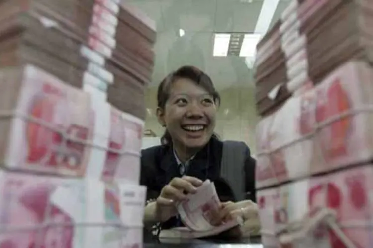 
	Funcion&aacute;ria de banco na China conta notas de iuan: pa&iacute;s est&aacute; dando mais espa&ccedil;o para bancos comerciais estabelecerem taxas de juros e tornar o iuan mais flex&iacute;vel
 (China Photos/Getty Images)