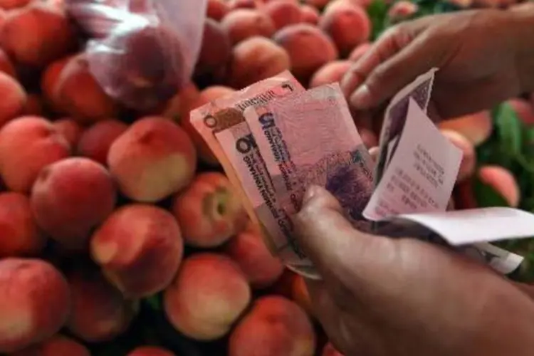 Homem segura notas de iuane chineses em Pequim: moeda é utilizada em apenas 1,4% das transações financeiras no mundo (Greg Baker/AFP)