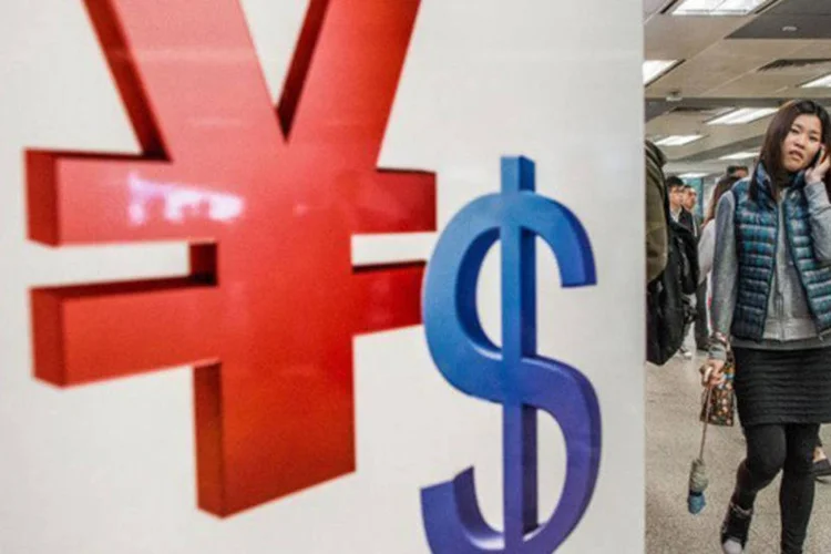 
	Mulher passa pelos sinais do yuan chin&ecirc;s e do d&oacute;lar americano: Pequim &eacute; acusado por seus principais interlocutores comerciais de manter um c&acirc;mbio artificialmente baixo
 (Philippe Lopez/AFP)