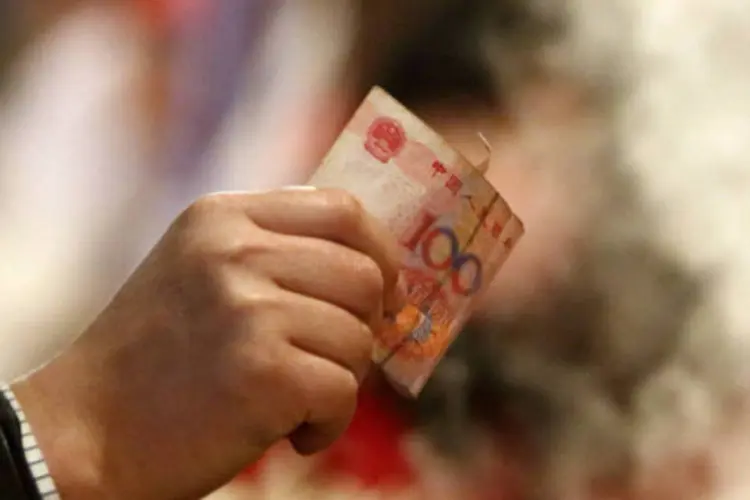 
	Homem segura nota de iuane, a moeda chinesa: na &uacute;ltima semana, o Banco Popular da China evidenciou sua preocupa&ccedil;&atilde;o com a press&atilde;o inflacion&aacute;ria
 (Tomohiro Ohsumi/Bloomberg)