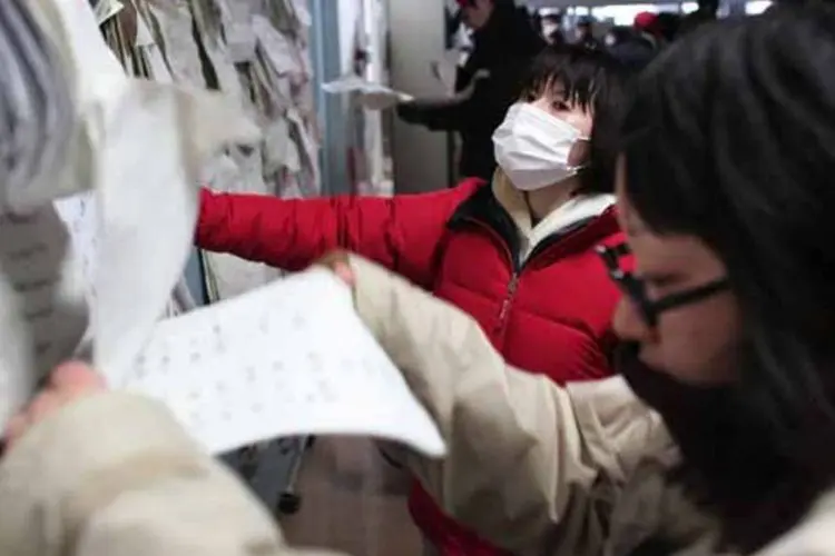 Pessoas procuram nome de desaparecidos em quadro, após terremoto  no Japão (Getty Images)