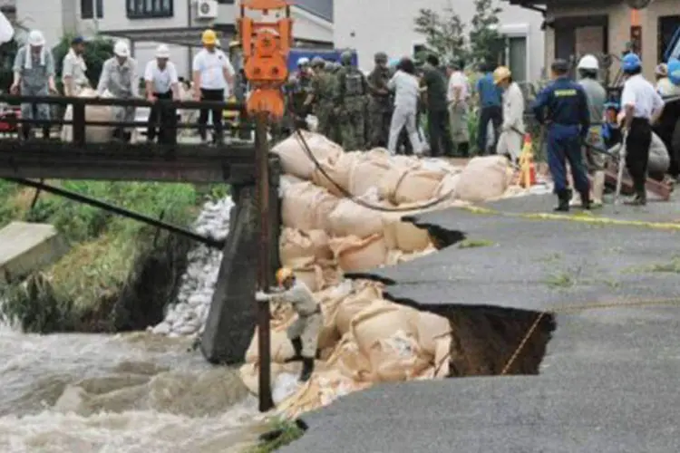 Funcionários avaliam danos causados pelas chuvas em cidade de Kurume, no Japão: o saldo nesta segunda-feira era de 28 mortos e quatro desaparecidos
 (Jiji Press/AFP)