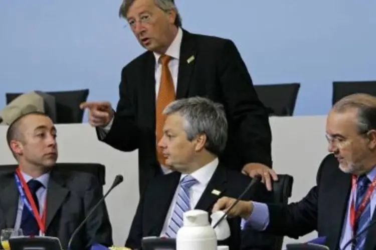 O presidente do Eurogrupo Jean-Claude Juncker (em pé) anunciou em coletiva a aprovação do pacote pelos ministros das Finanças da Zona do Euro (Getty Images)