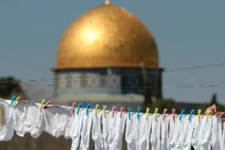 Mulher palestina pendura roupas em varal, na área anexada por Israel em Jerusalém Oriental: espera-se que negociações de paz acabem antes do final de abril em "acordo marco" (AFP)