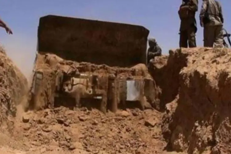 
	Jihadistas do EIIL passam com trator no meio de muro de areia, entre Iraque e S&iacute;ria, criando caminho para ve&iacute;culos
 (ALBARAKA NEWS/AFP)