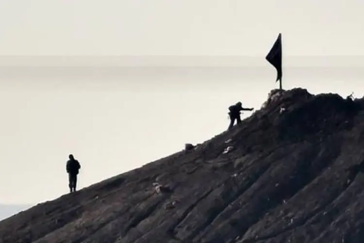 
	Supostos jihadistas hasteiam uma bandeira em uma colina na S&iacute;ria
 (Aris Messinis/AFP)