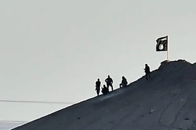 
	Jihadistas hasteiam uma bandeira do Estado Isl&acirc;mico em uma colina da cidade s&iacute;ria de Kobane
 (Aris Messinis/AFP)