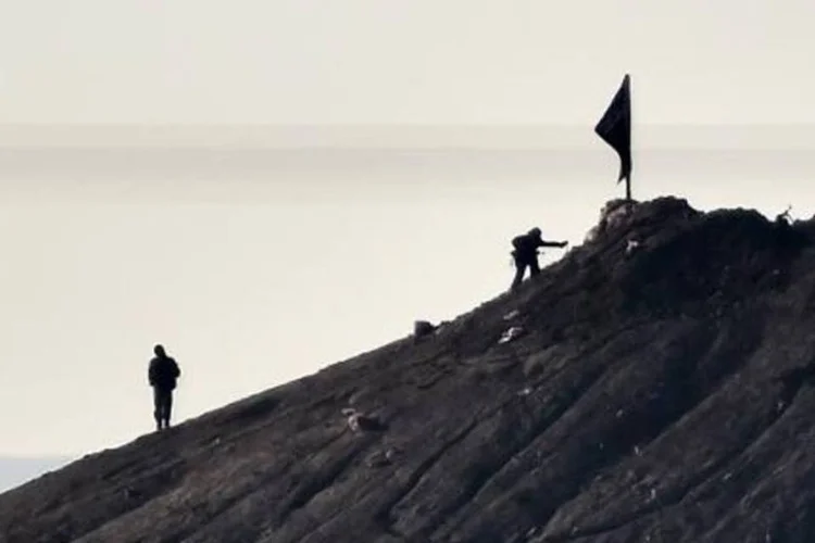 
	Supostos jihadistas hasteiam uma bandeira em uma colina no leste de Kobane: confrontos em todo o Iraque mataram pelo menos 58 membros do grupo
 (Aris Messinis/AFP)